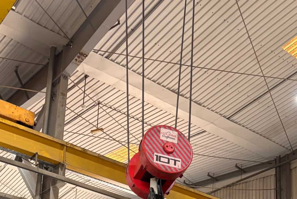 Bucking Unit Pipe Loading: Crane, Support, Alignment, and Operator Flow 2 Red crane hook with 10-ton capacity in oilfield equipment warehouse.